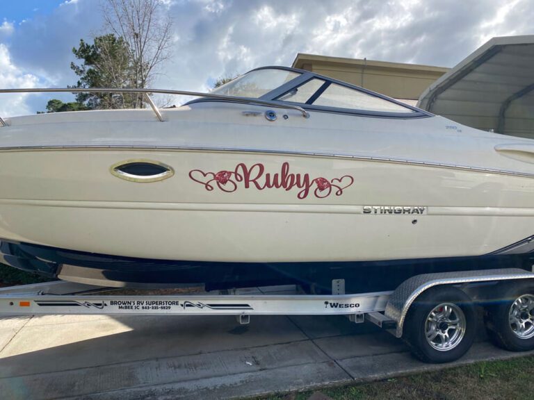 A cream-colored cabin cruiser with custom red script lettering reading Ruby on its hull.