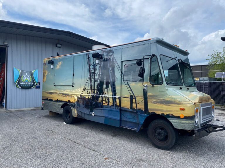 A white step van wrapped in a photo-realistic sunset scene of a shrimp boat at dock.
