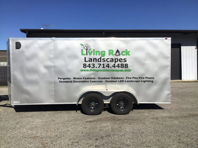 A white enclosed trailer lists landscaping services under the Living Rock Landscapes logo and phone number.