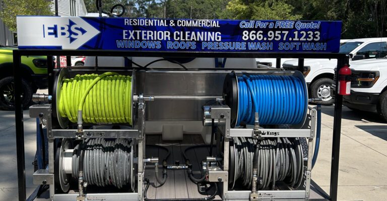 A close-up of a pressure washing trailer's hose reels beneath an EBS exterior cleaning banner.