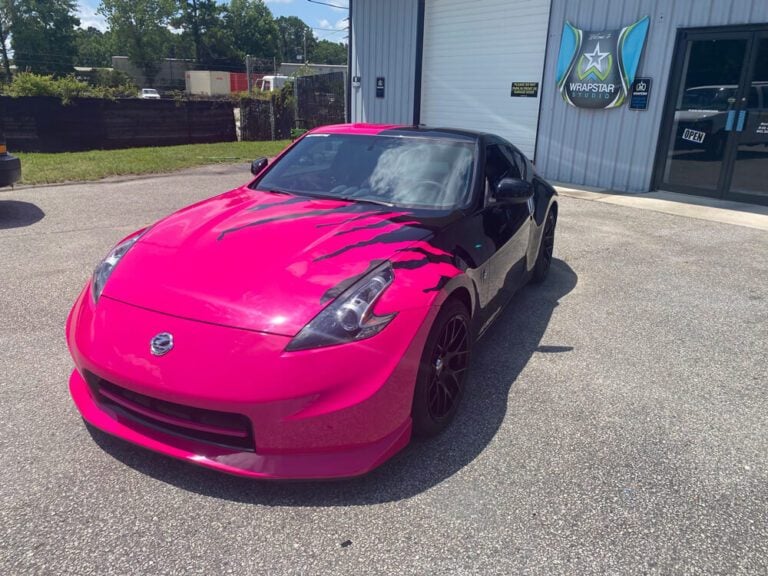 A pink and black claw-mark wrap covers a sports coupe parked outside the Wrapstar Studio storefront.