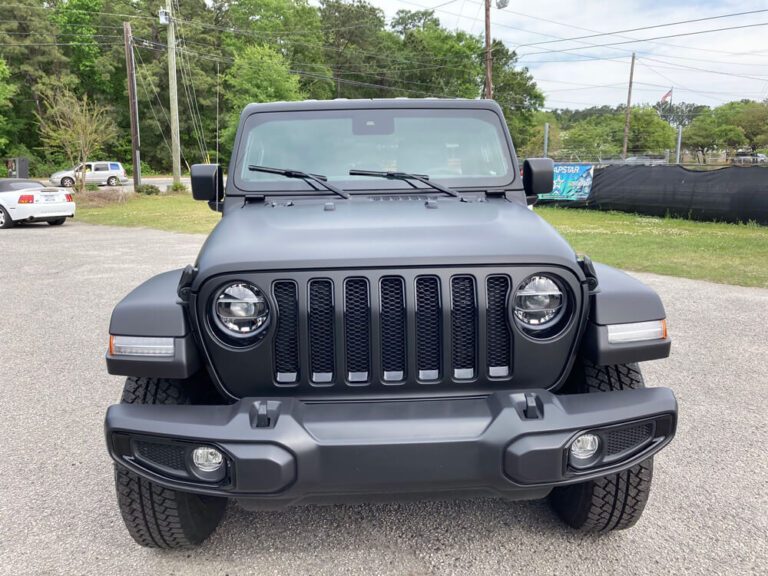 A matte black wrapped Jeep Wrangler parked outdoors, viewed straight on from the front.