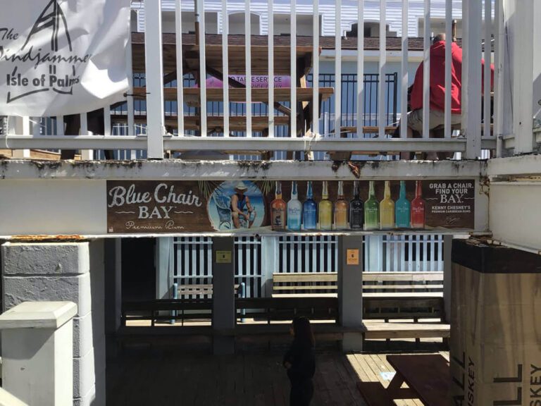 A beachfront bar displays printed Blue Chair Bay rum signage beneath an outdoor deck on Isle of Palms.