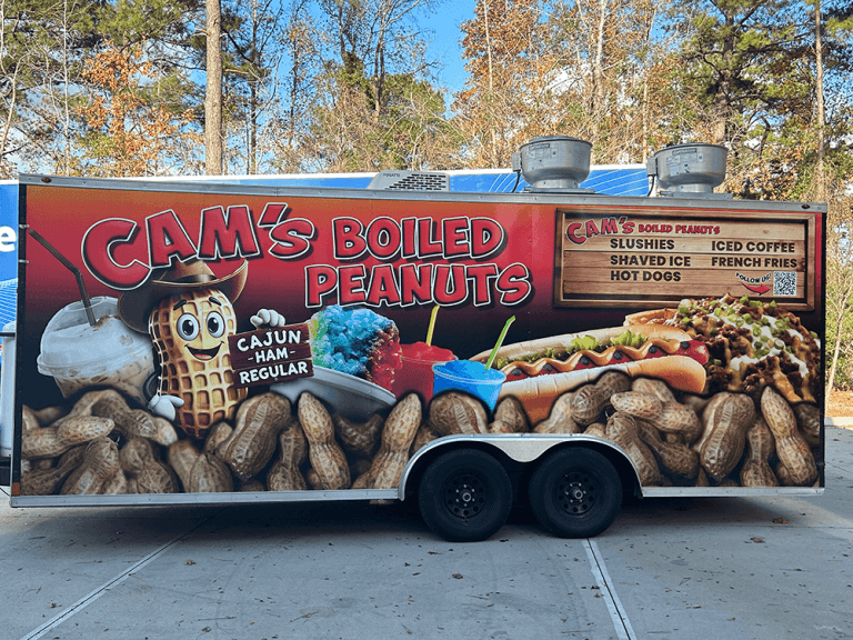 A food trailer wrapped with Cam's Boiled Peanuts branding and a menu board of snacks and drinks.