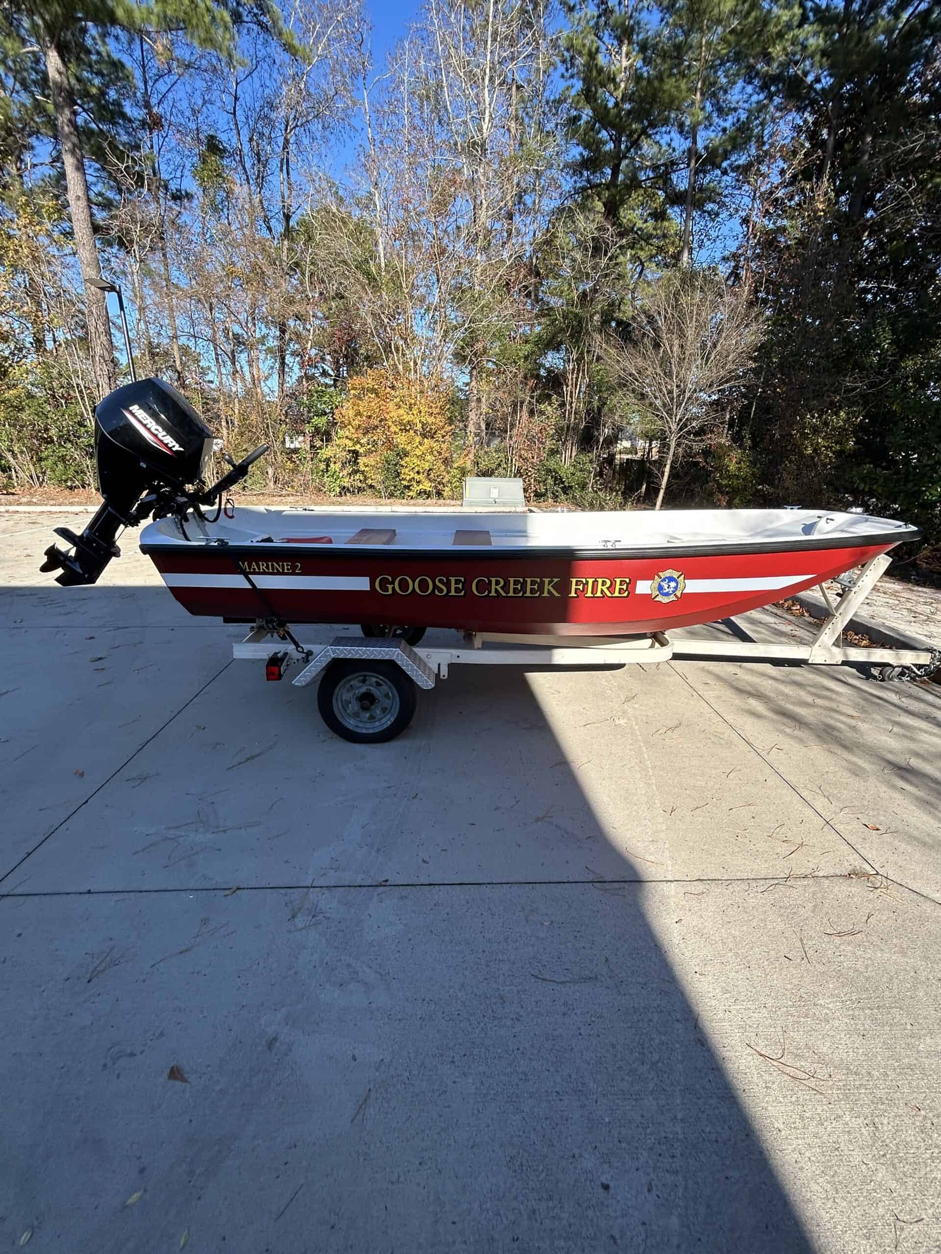 Fire department boat with vibrant red and black wrap, featuring "GOOSE CREEK FIRE" branding.