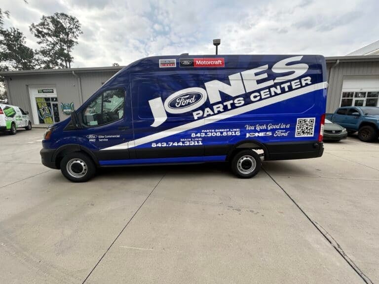 A blue Ford Transit van wrapped in Jones Ford Parts Center branding parked outside the shop.