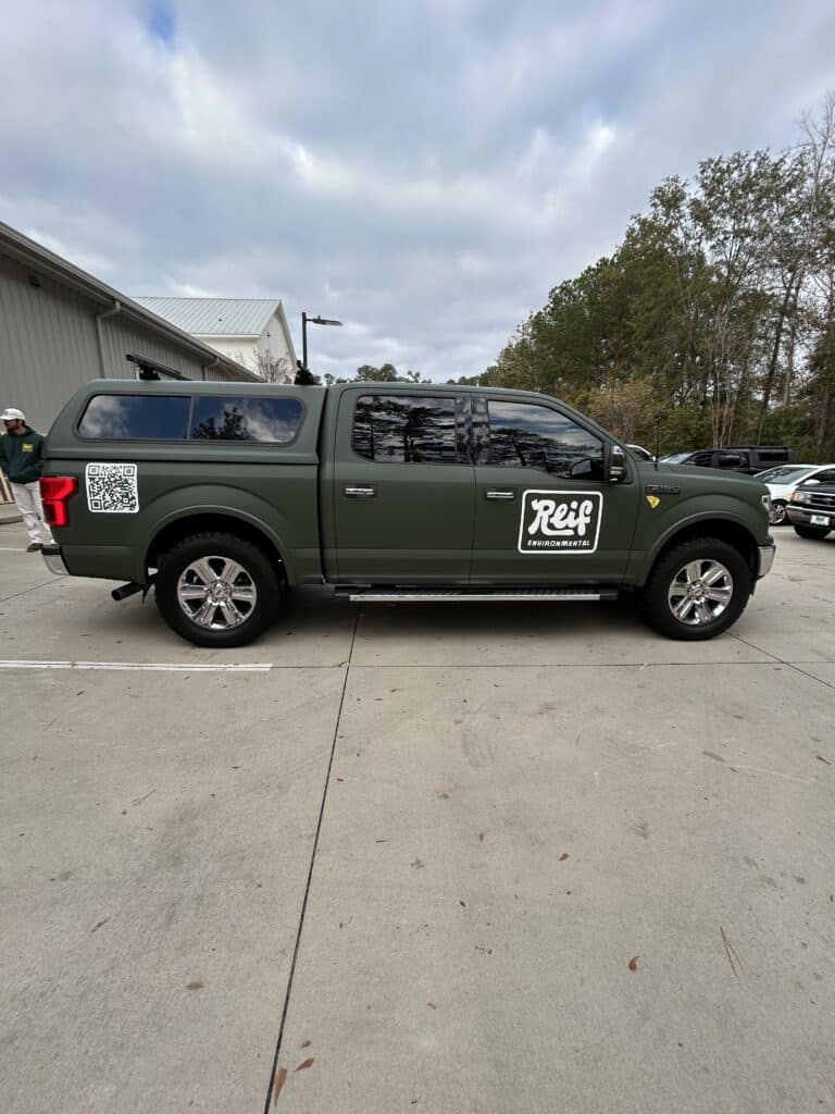 Vehicle wrap on a dark green pickup truck with "Reif" logo for advertising.