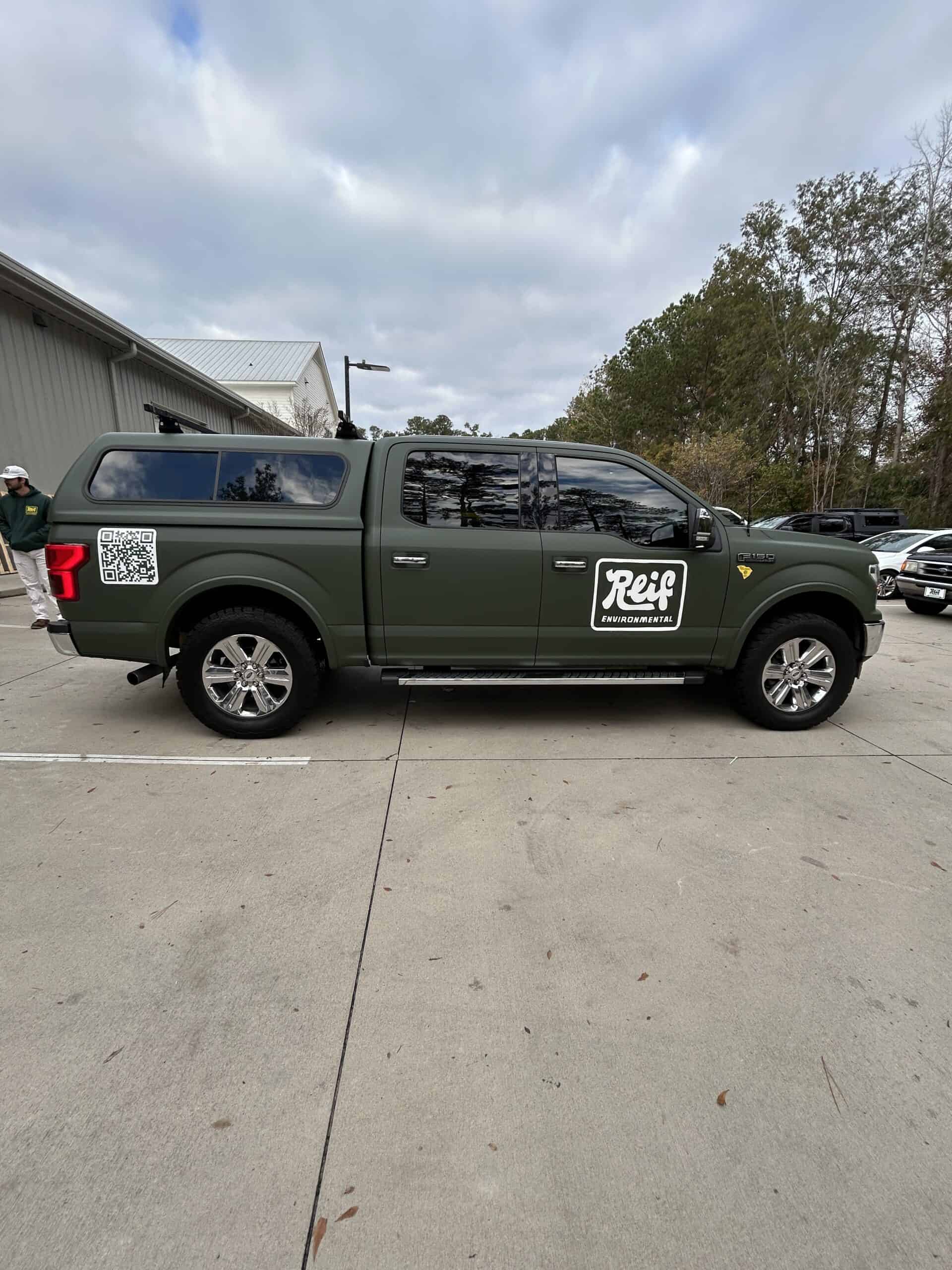 Vehicle wrap on a dark green pickup truck with "Reif" logo for advertising.