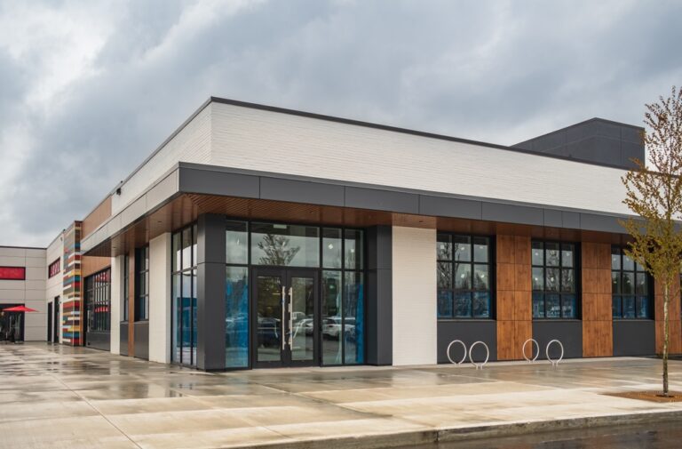 A modern retail storefront with large glass windows and wood paneling under a cloudy sky.