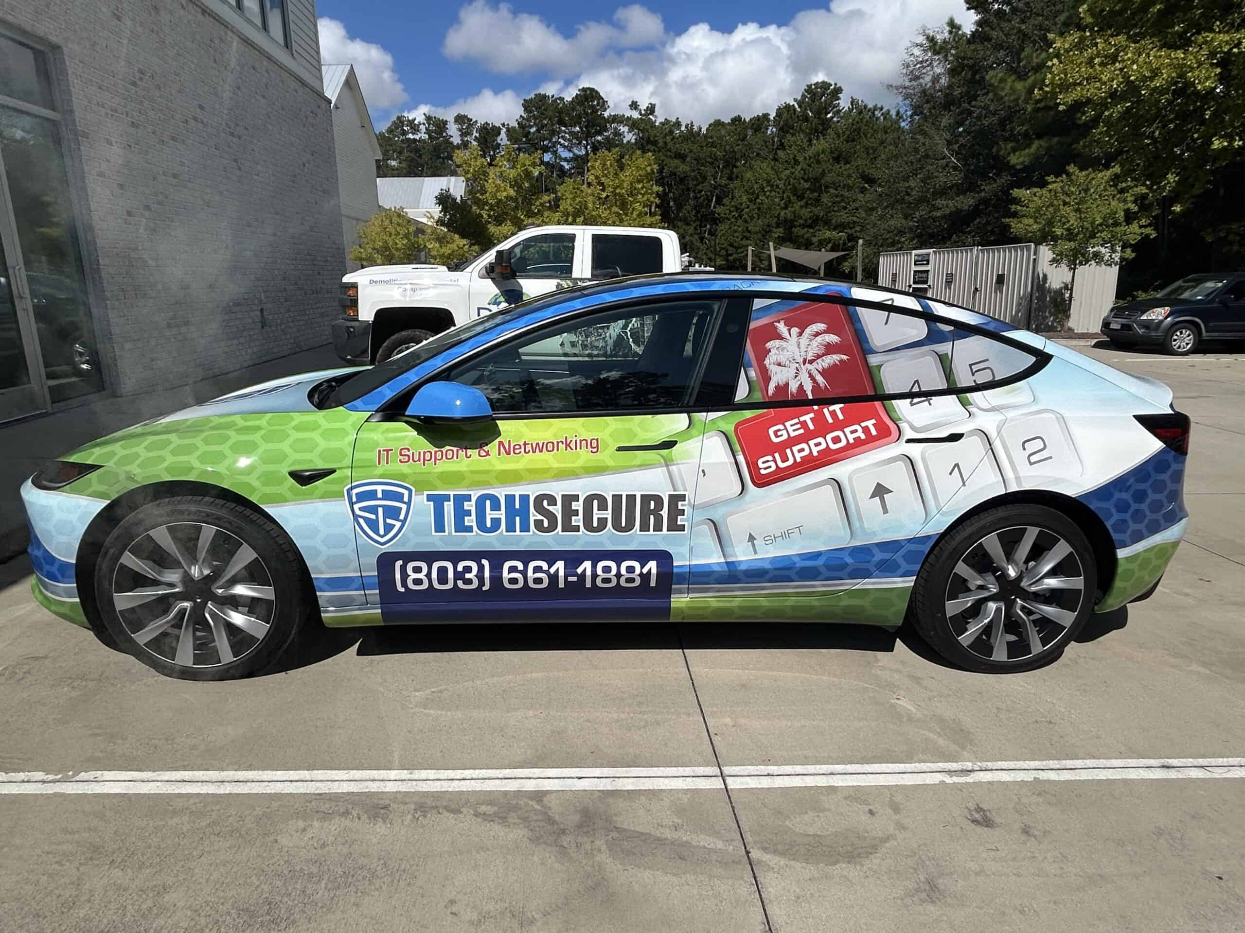A Tesla wrapped in green and blue TechSecure IT support branding parked near a building.